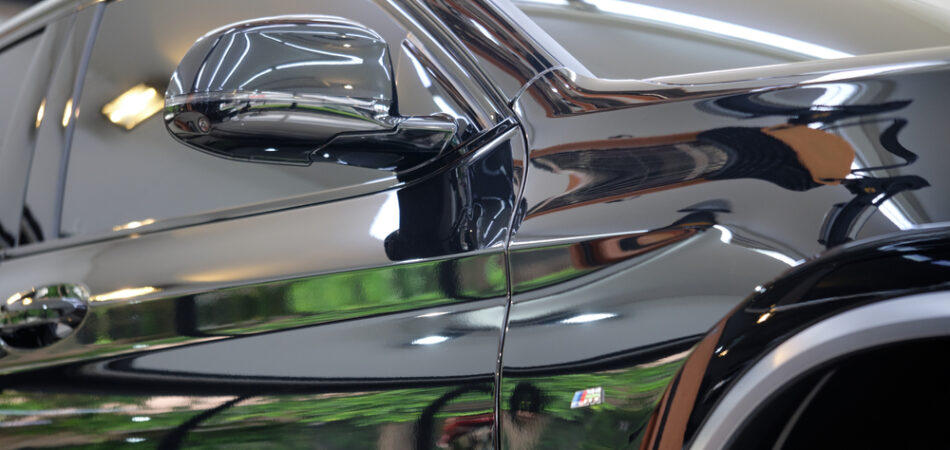 Side,view,of,shiny,black,sedan,with,reflection,on,door