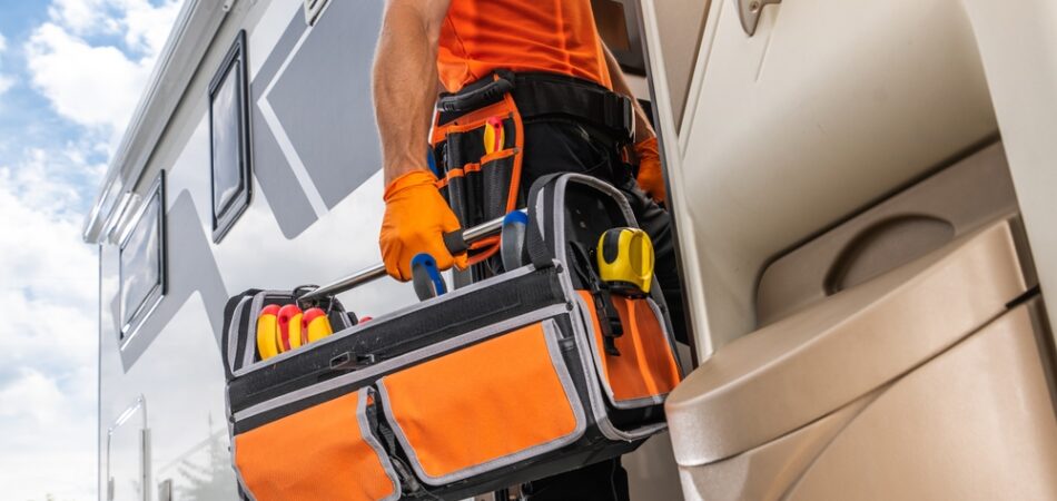 A,technician,dressed,in,orange,is,entering,a,recreational,vehicle