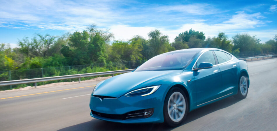 A,blue,coloured,electric,car,cruising,on,highway,with,clear,blue